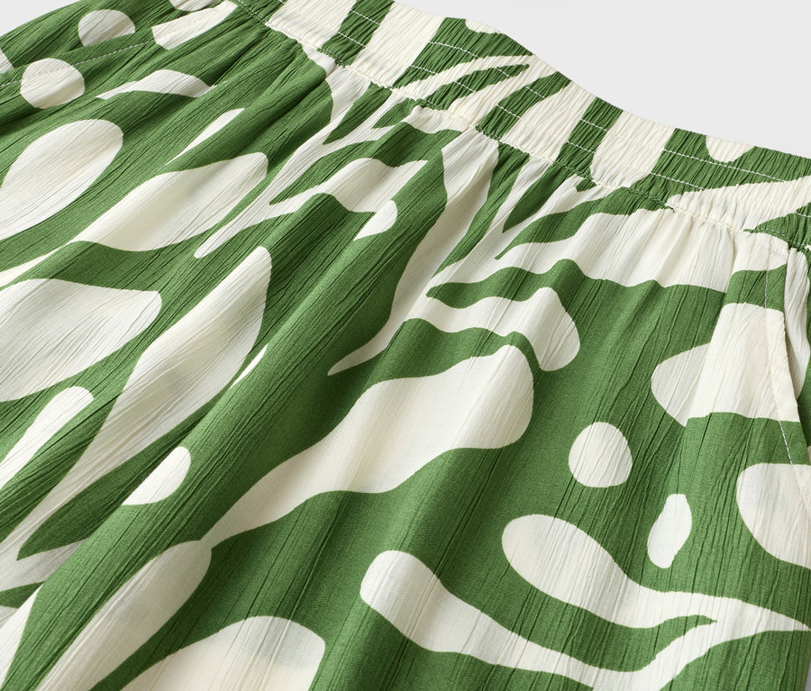 Gros plan d'un pantalon vert et blanc avec un motif abstrait et une ceinture élastique.