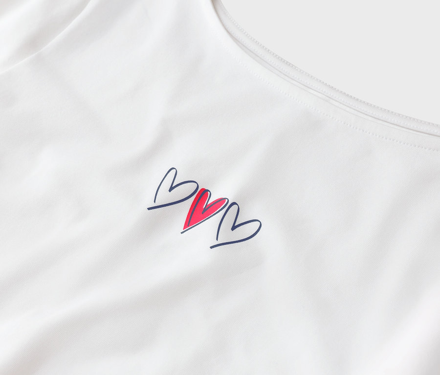Haut blanc avec trois cœurs, un rouge et deux bleus.