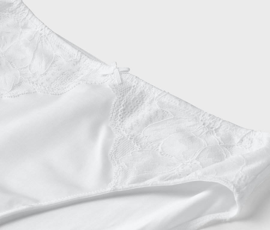 Vue détaillée d'un slip blanc avec des détails en dentelle et un petit nœud.