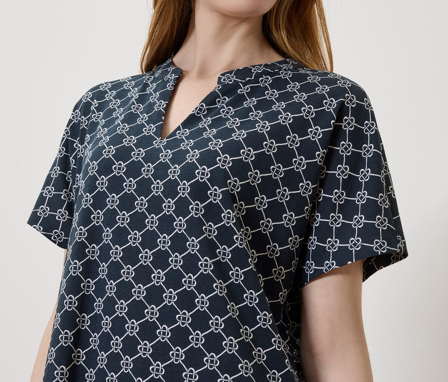Une femme porte un chemisier bleu marine avec un motif blanc.