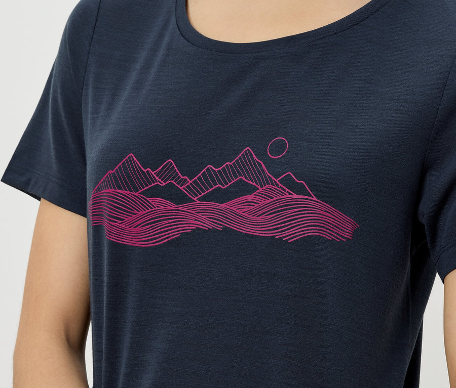 Gros plan d'une personne portant un t-shirt bleu marine avec un imprimé rose représentant un paysage de montagne.