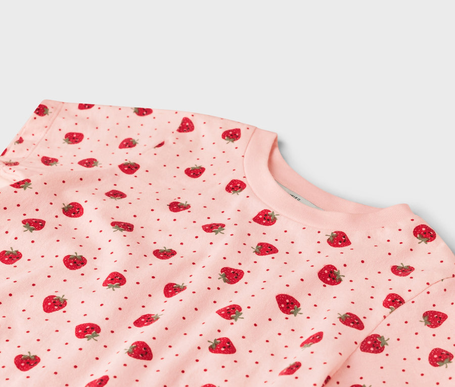 Gros plan sur un t-shirt rose à motifs de fraises.