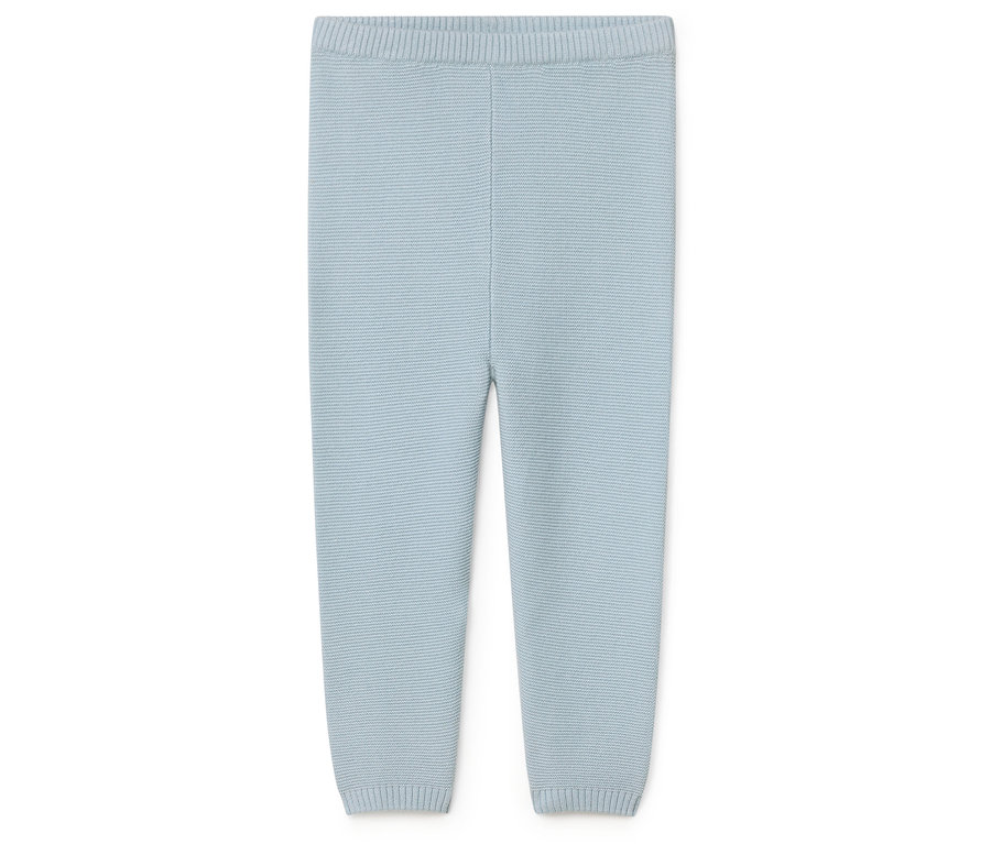 Un pantalon en tricot bleu clair pour bébés est posé sur un fond blanc.