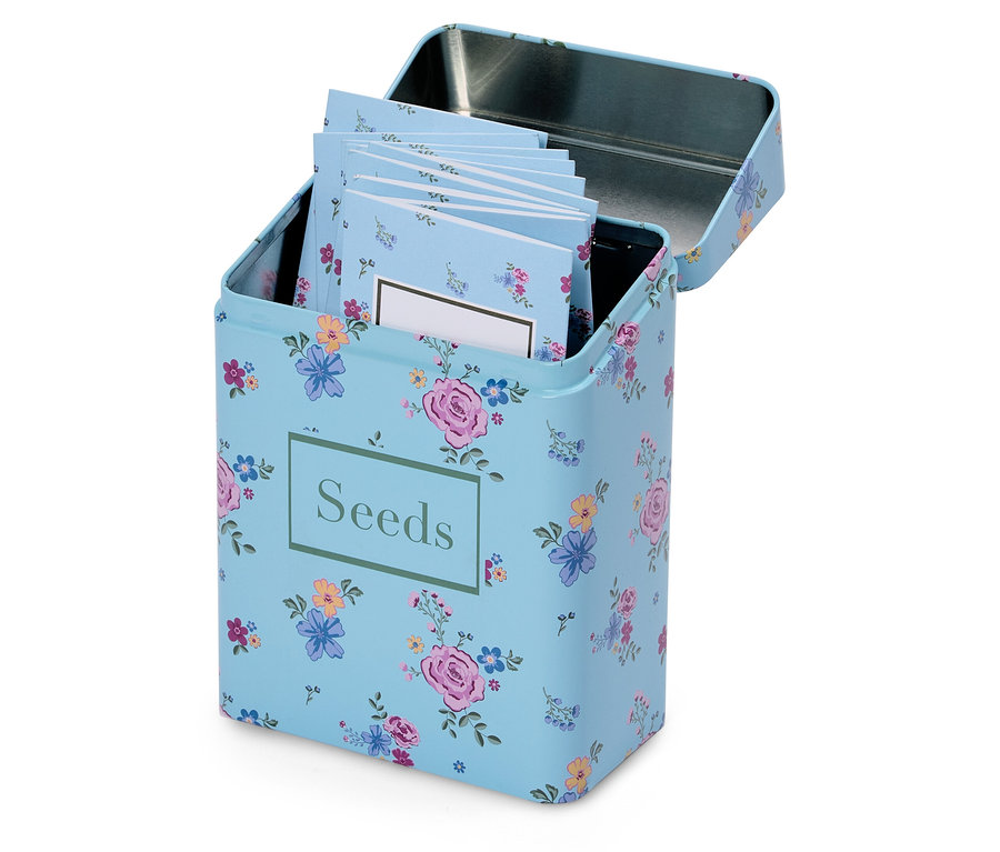 Une boîte à graines fleurie bleu clair ouverte avec l'inscription "Seeds" et plusieurs petits blocs-notes à l'intérieur.