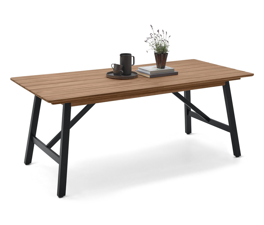 Sur une table en bois avec des pieds noirs, il y a une tasse, une soucoupe, un livre et une plante.