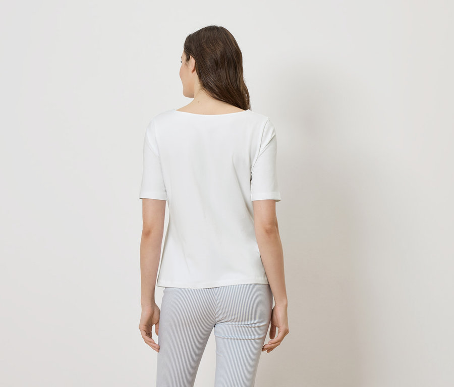 Vue de dos d'une femme aux cheveux bruns portant un t-shirt blanc et un pantalon rayé bleu et blanc.