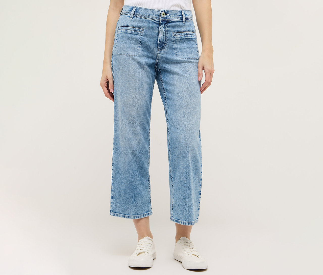 Une femme porte un culotte Angels Denim «
Linn Smart
» bleu clair et des chaussures blanches sur fond blanc.