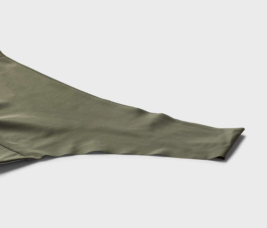 Gros plan sur une manche en tissu vert olive avec un ourlet ondulé sur un fond gris.