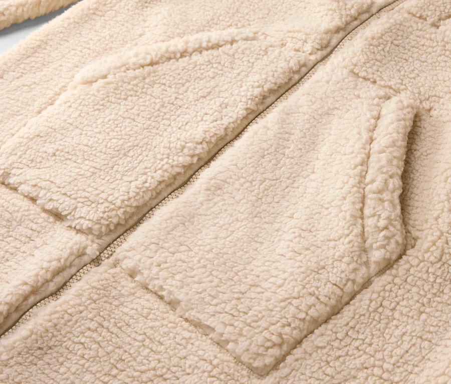 Gros plan d'une veste polaire beige clair avec fermeture éclair et poches plaquées.
