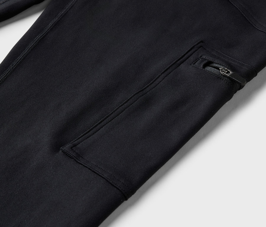 Gros plan sur un pantalon noir avec une poche zippée.