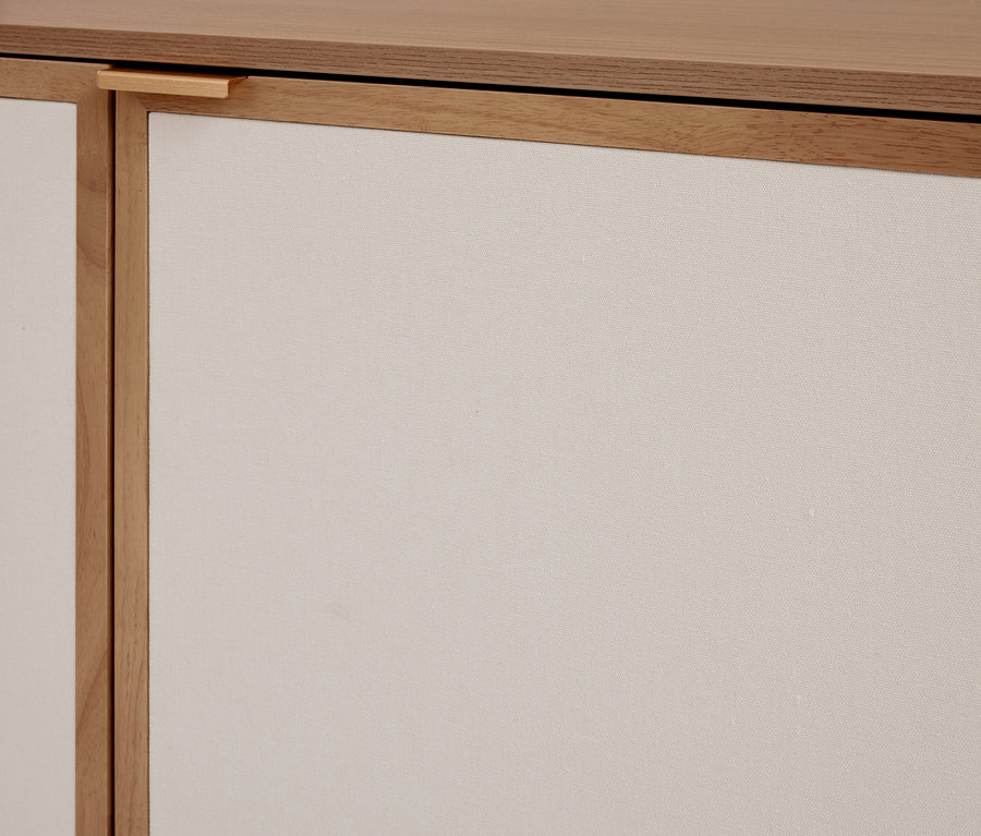 Meuble en bois clair avec des panneaux en tissu beige clair et une petite poignée en bois.