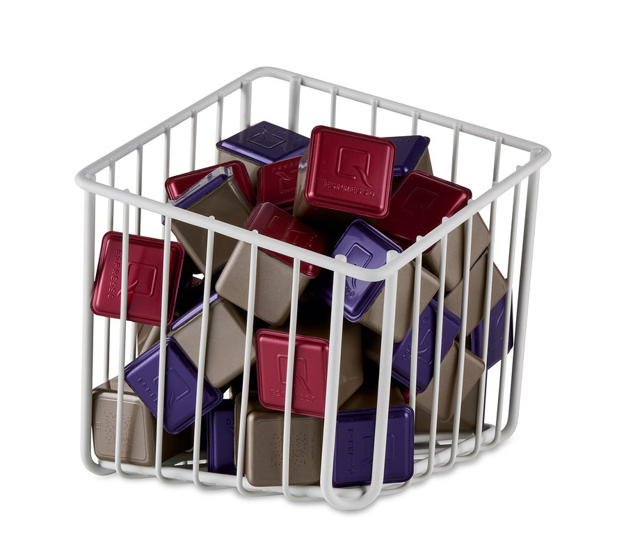 Un panier à capsules blanc rempli de capsules rouges, violettes et marron.