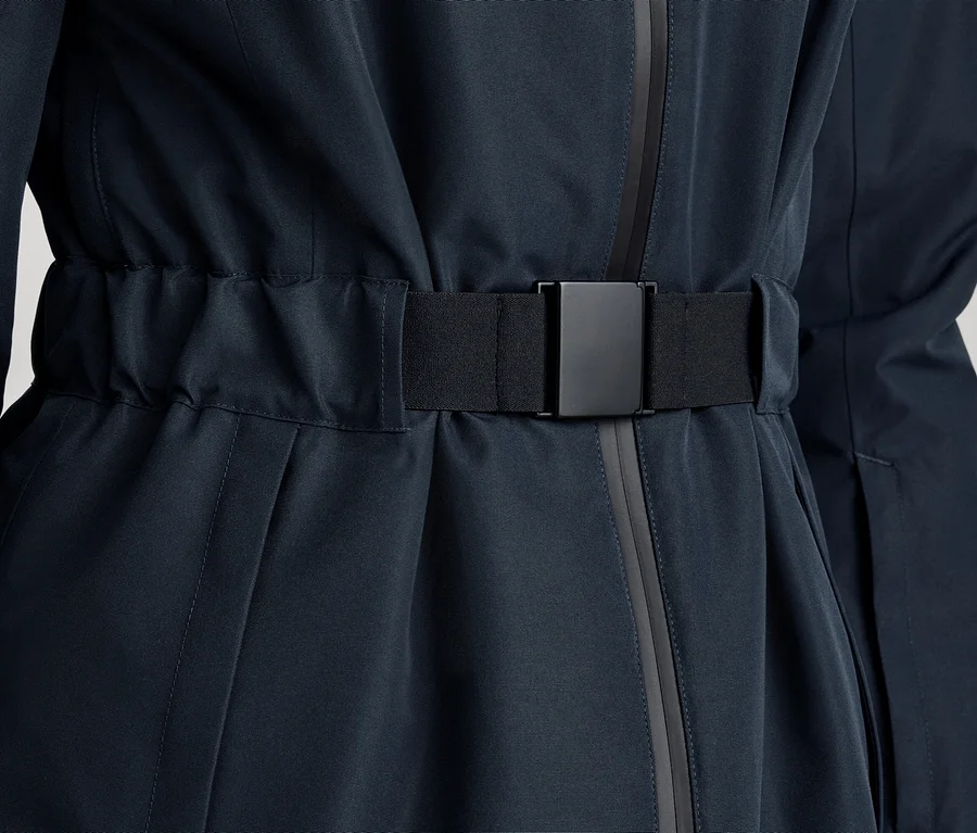 Gros plan d'une veste ou d'un manteau bleu foncé avec une ceinture élastique noire et une boucle rectangulaire noire, cintrant la taille.