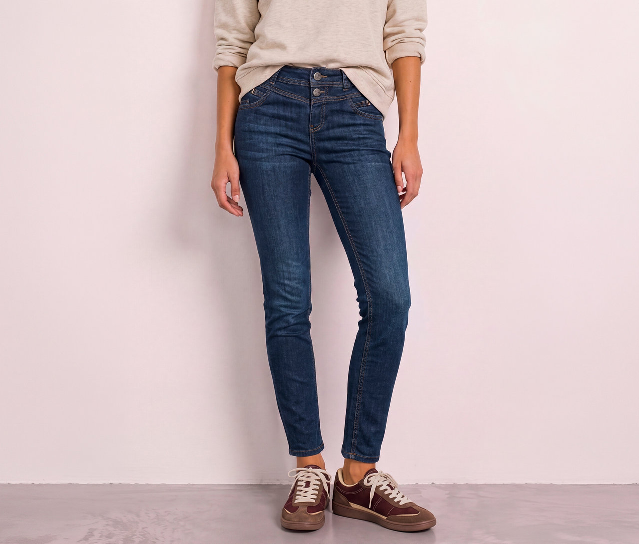 Personne debout, portant un jean Street One bleu foncé taille haute et des baskets marron.