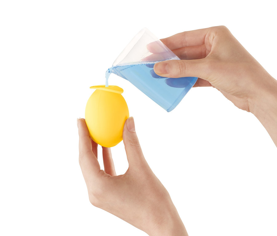 Une personne verse du liquide bleu d'un bécher dans un embout détartrant jaune pour robinet.