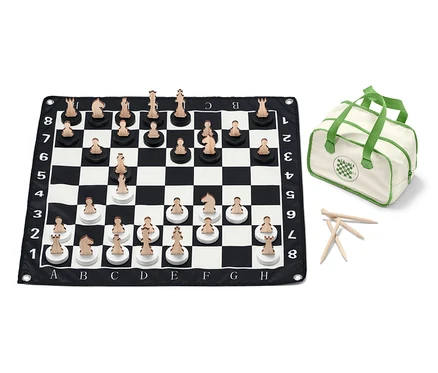 Un jeu d'échecs XL est disposé sur un échiquier noir et blanc avec des pièces en bois, et il y a un sac à côté.