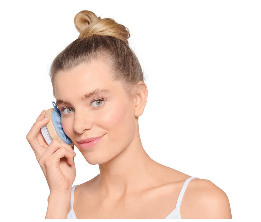 Femme utilisant une brosse de nettoyage pour le visage.