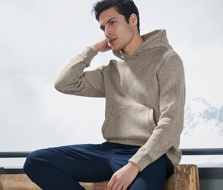 Homme assis sur un banc, portant une veste en maille polaire.