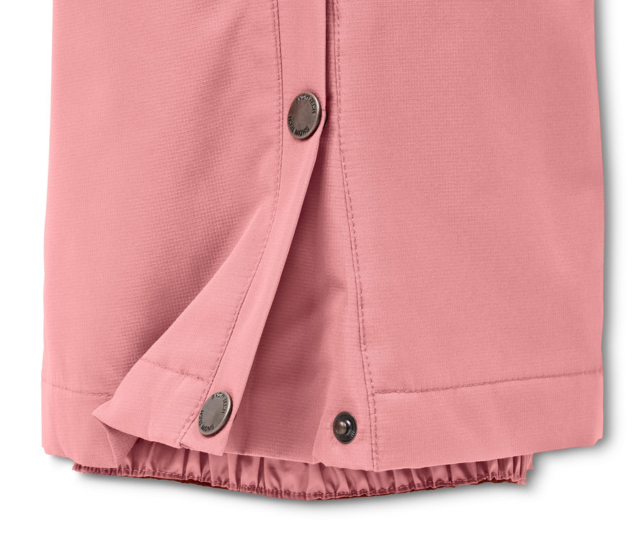 Gros plan sur un pantalon de ski et de snowboard rose avec fermeture à bouton-pression.