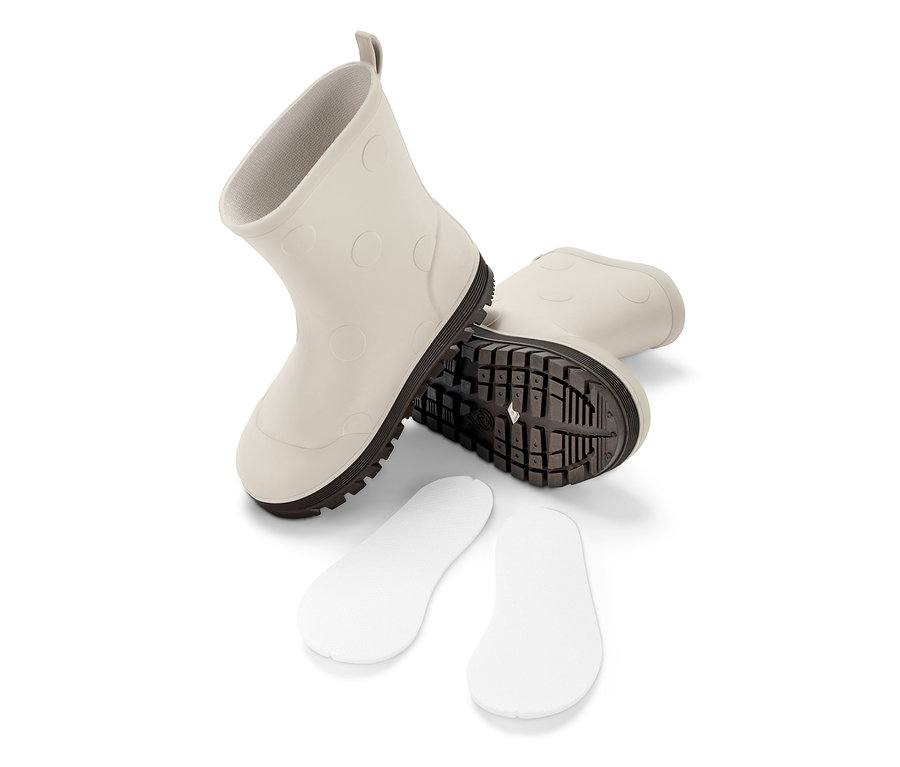 Deux bottes en caoutchouc et des semelles sur fond blanc.