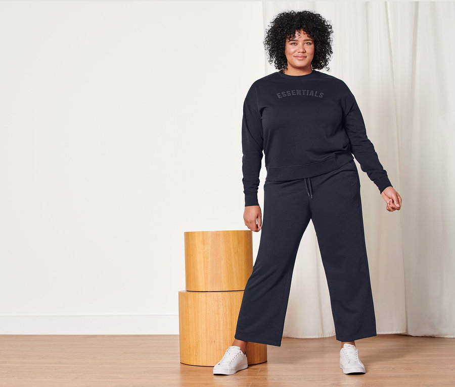 Femme posant en pantalon de survêtement et sweat-shirt bleu foncé.