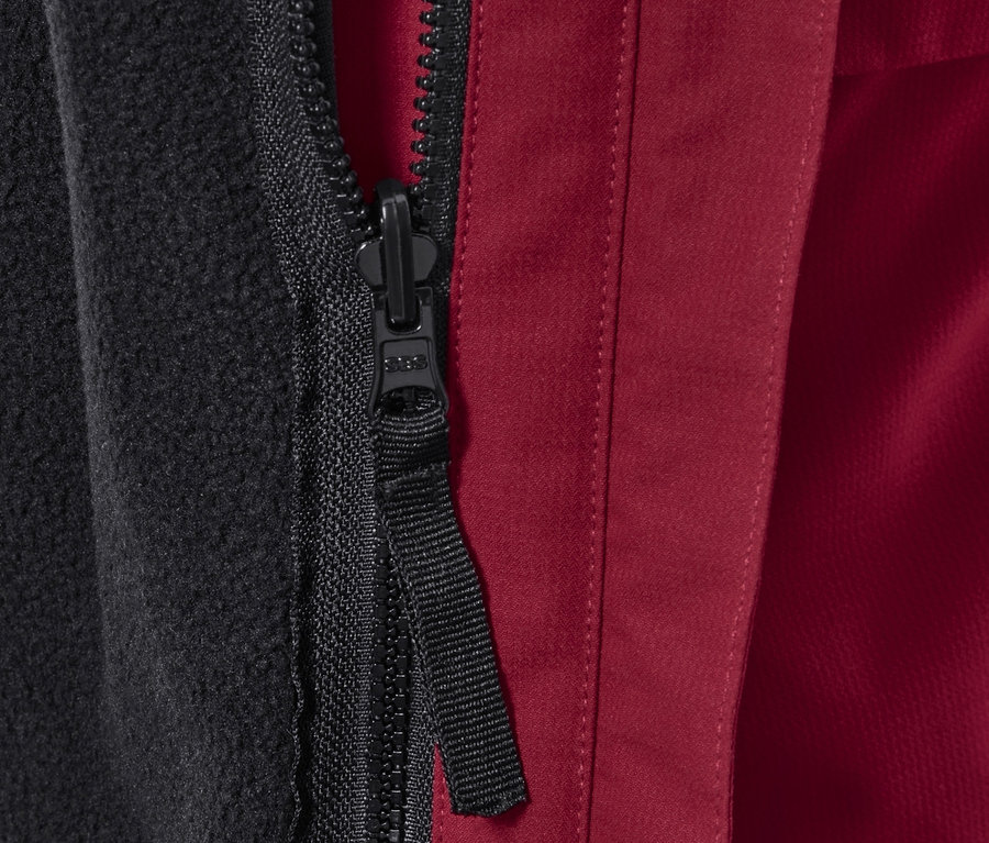 Gros plan sur la fermeture éclair d'une veste d'extérieur avec doublure polaire noire et tissu extérieur rouge.