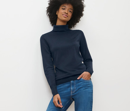 Femme afro-américaine portant un pull à col roulé en maille fine bleu foncé et un jean.