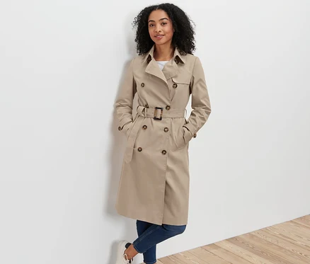 Femme posant en trench-coat beige.
