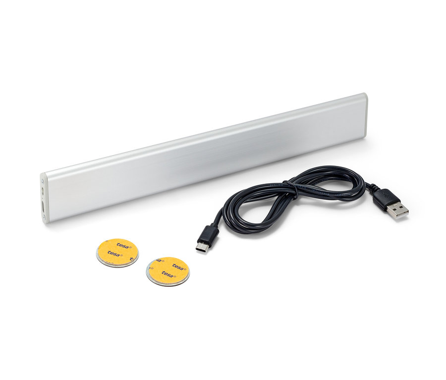 Une lampe multifonctions LED à batterie, un câble noir et deux tampons adhésifs sur fond blanc.