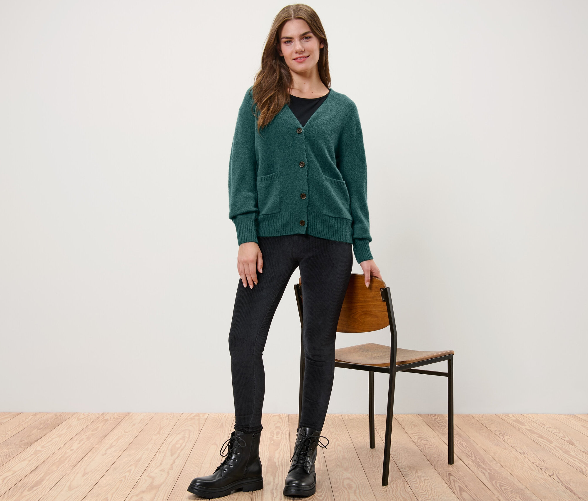 Une femme debout portant une jaquette en maille vert foncé avec de la laine.