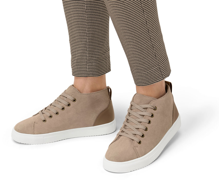 Jambes d'une personne portant un pantalon à carreaux et des baskets doublées en cuir velours.