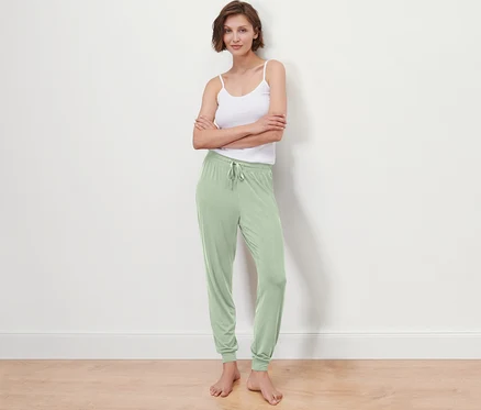 Femme posant en pantalon de pyjama et débardeur.