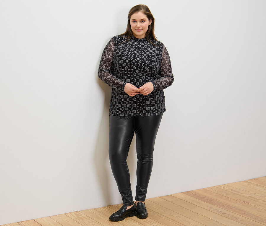 Femme posant en legging aspect cuir et haut manches longues à col roulé en mesh imprimé.