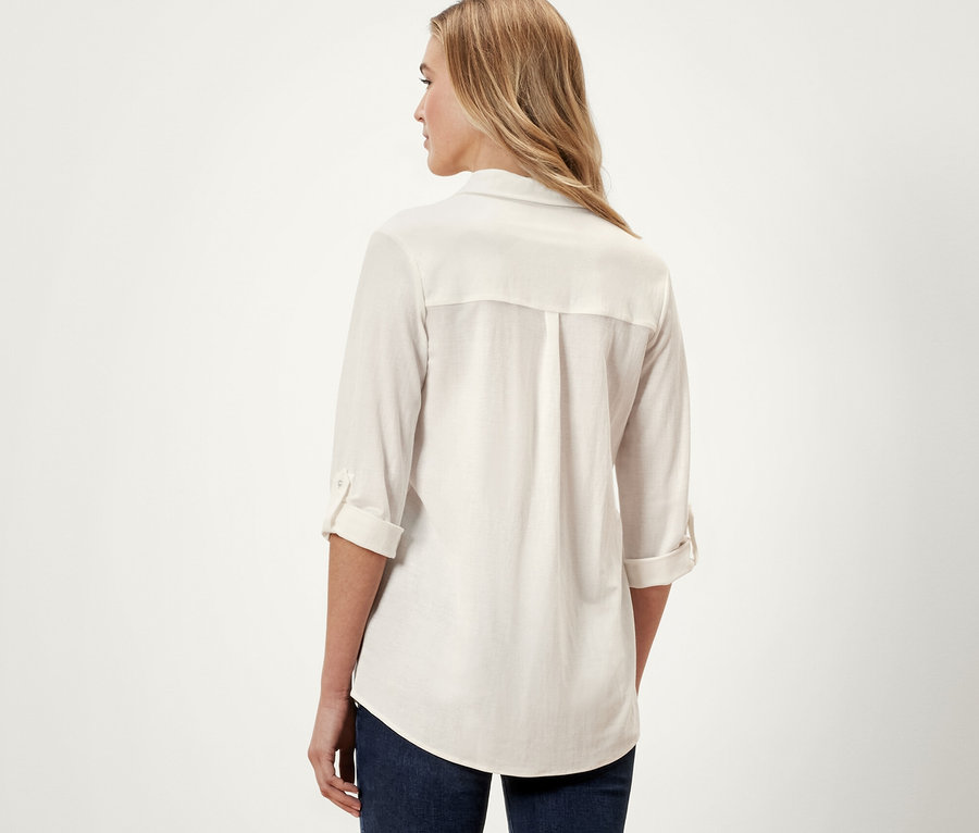 Vue arrière d'une femme portant un chemisier en jersey piqué blanc crème et un jean bleu.