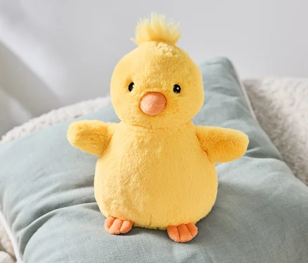 Un poussin en peluche est assis sur un coussin.