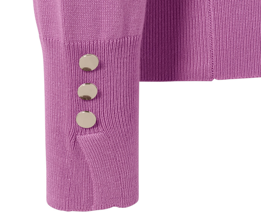 Détail d'un pull en maille fine avec trois boutons argentés sur la manche.