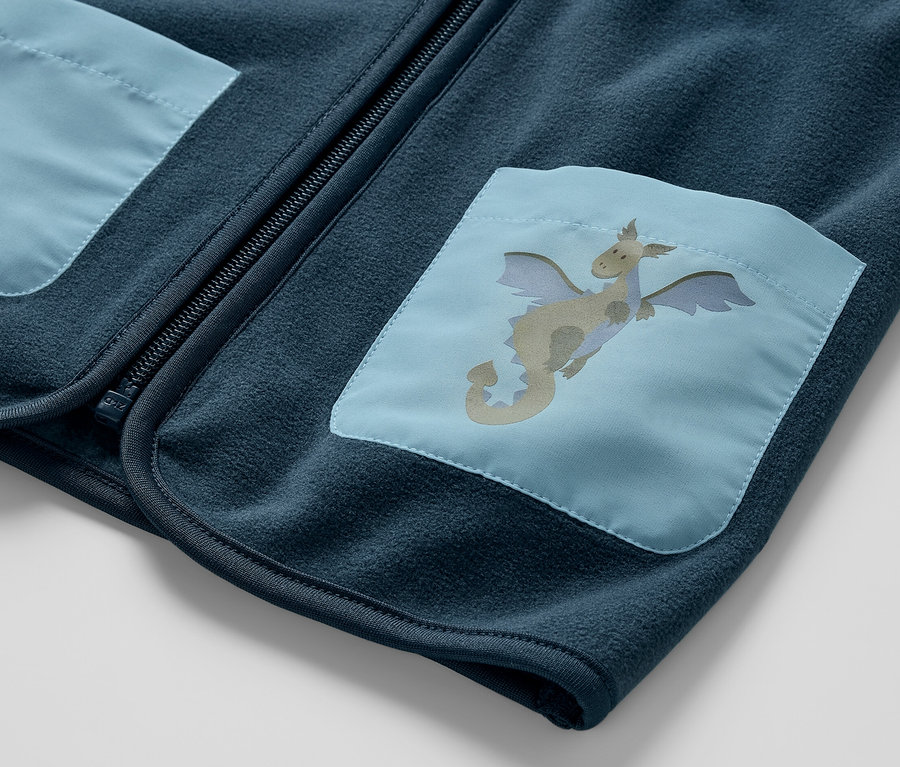 Gros plan sur un gilet sans manches polaire pour enfant, dragon, avec un patch dragon bleu sur la poche.