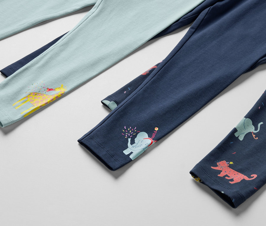 Détail de trois leggings pour enfants, un bleu clair avec une girafe, un bleu foncé avec un éléphant et un bleu foncé avec des animaux.
