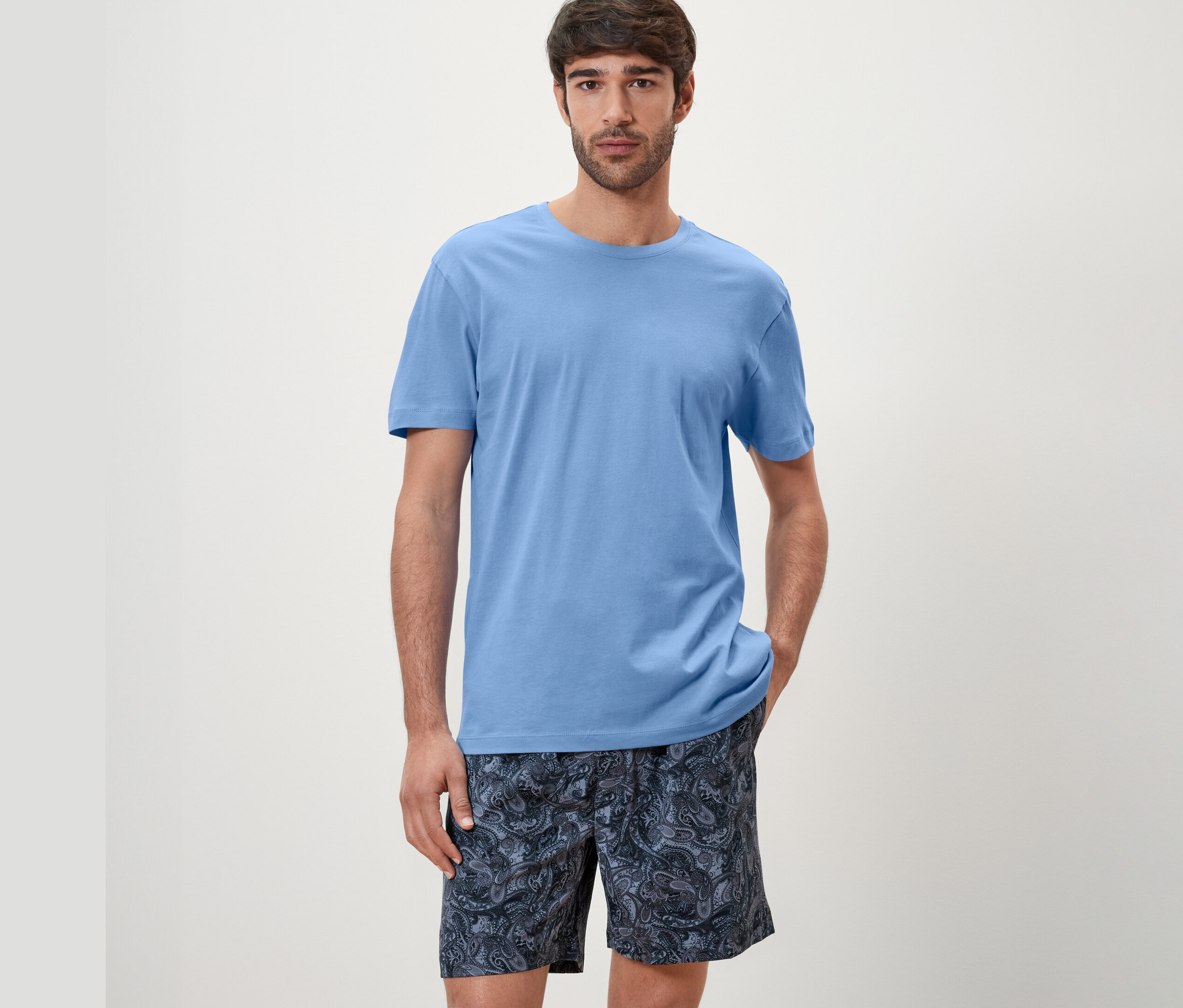 Un homme porte un ensemble de pyjama shorty bleu.
