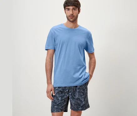 Un homme porte un ensemble de pyjama shorty bleu.