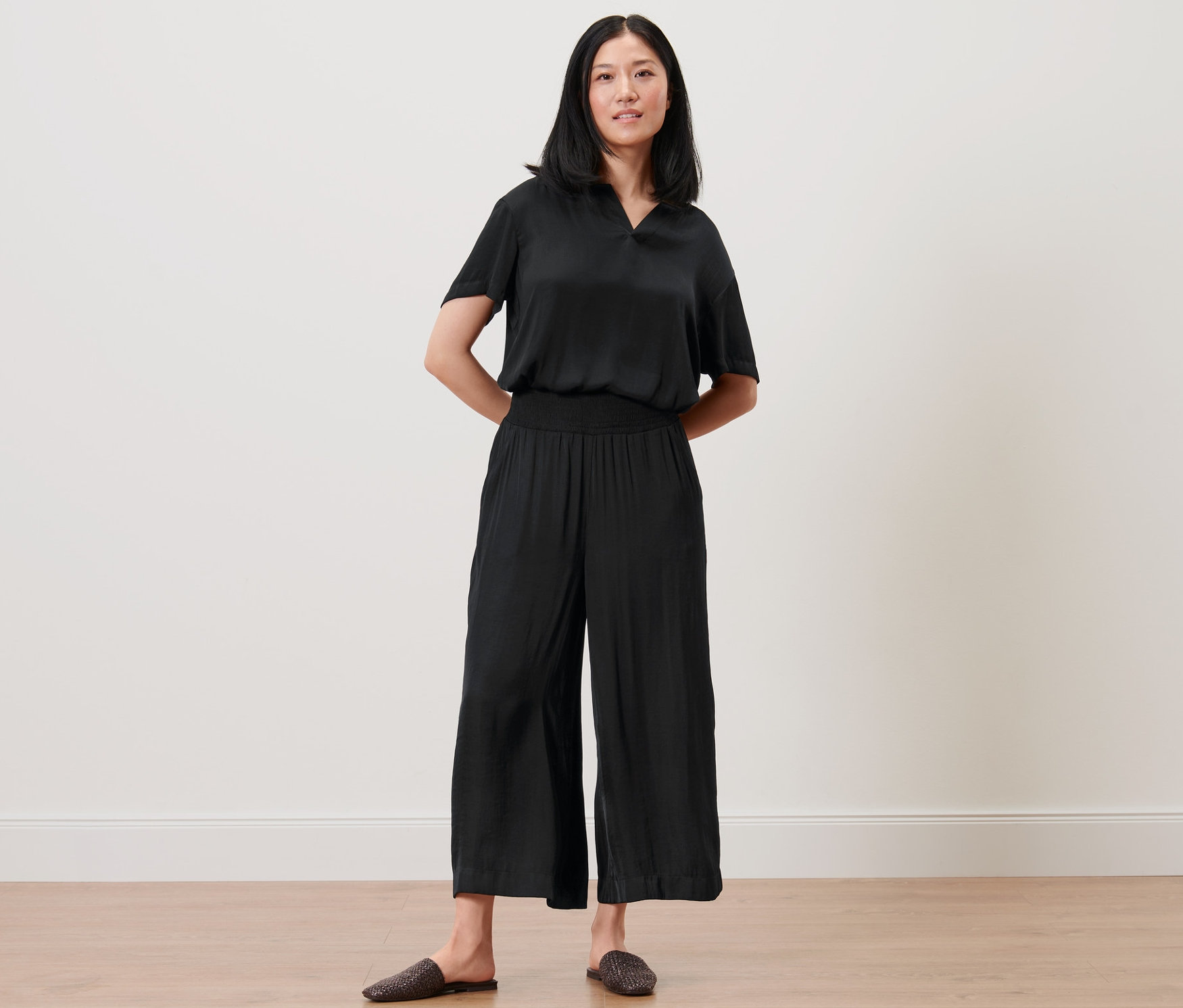 Femme posant en jupe-culotte et haut en satin noirs.