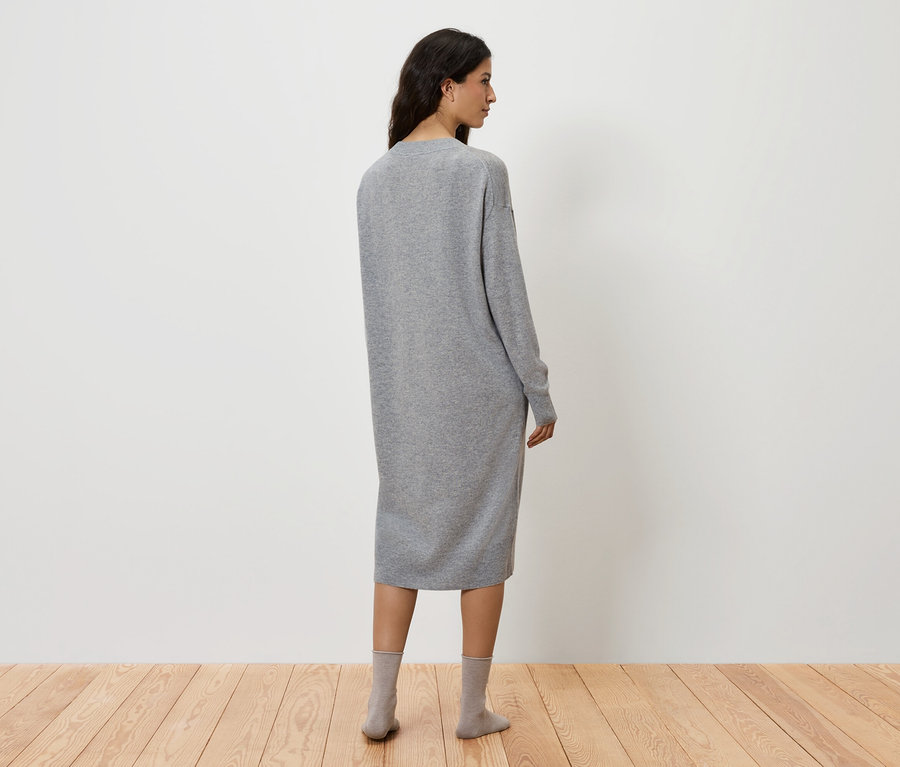 Une femme, vue de dos, porte une robe grise et des chaussettes grises.