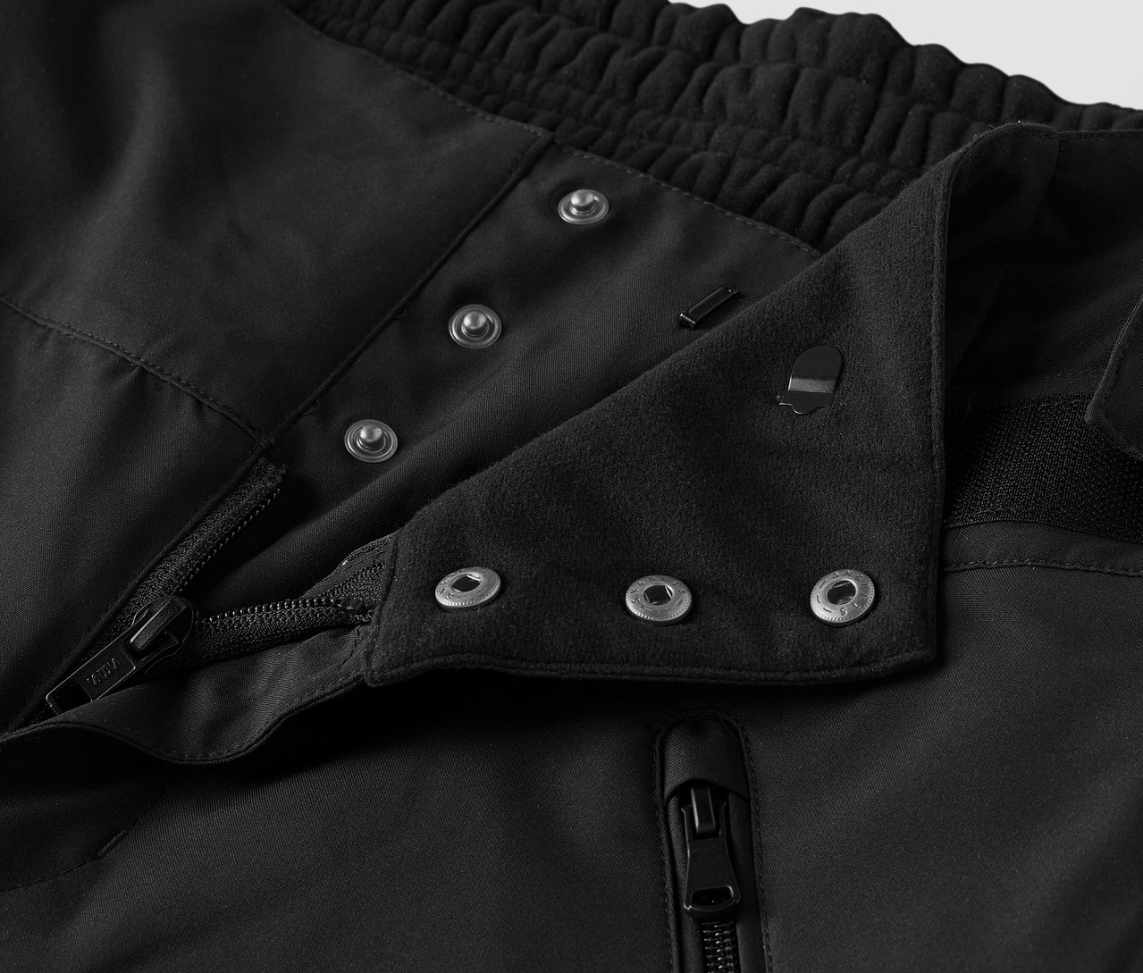 Gros plan sur un tissu noir avec des boutons et une fermeture éclair.
