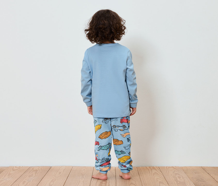 Un enfant, dos à la caméra, porte un pyjama bleu avec un imprimé de petites voitures.