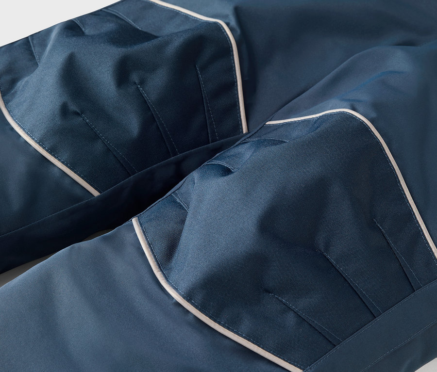 Gros plan d'un pantalon bleu avec passepoil blanc et poches.