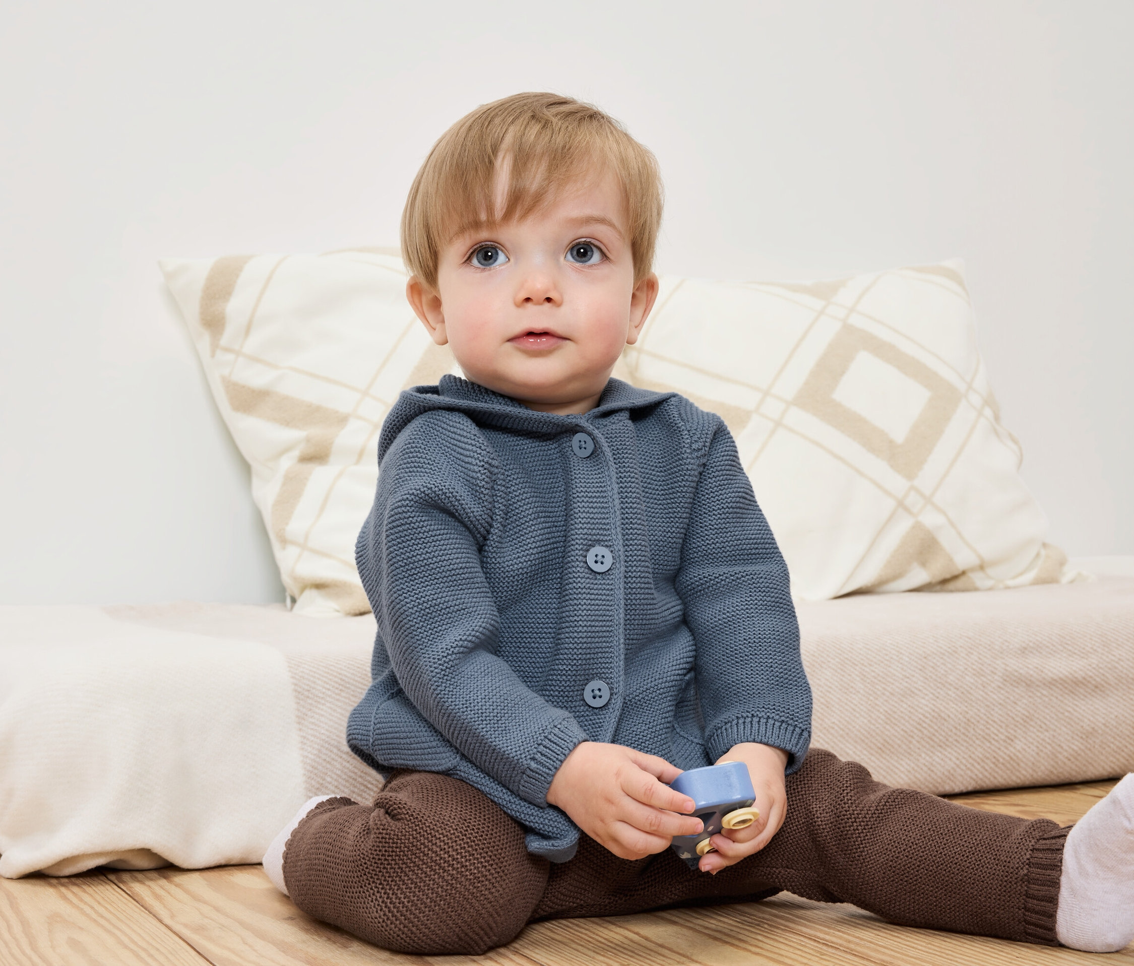 Un enfant est assis par terre avec un jouet à la main.