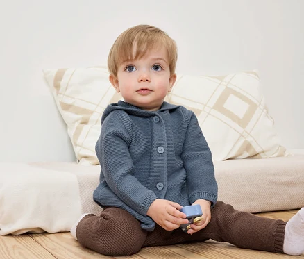 Un enfant est assis par terre avec un jouet à la main.