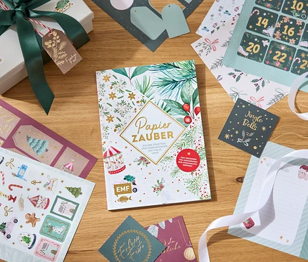 Papiers décoratifs, autocollants et boîte cadeau avec un ruban sur une table en bois.
