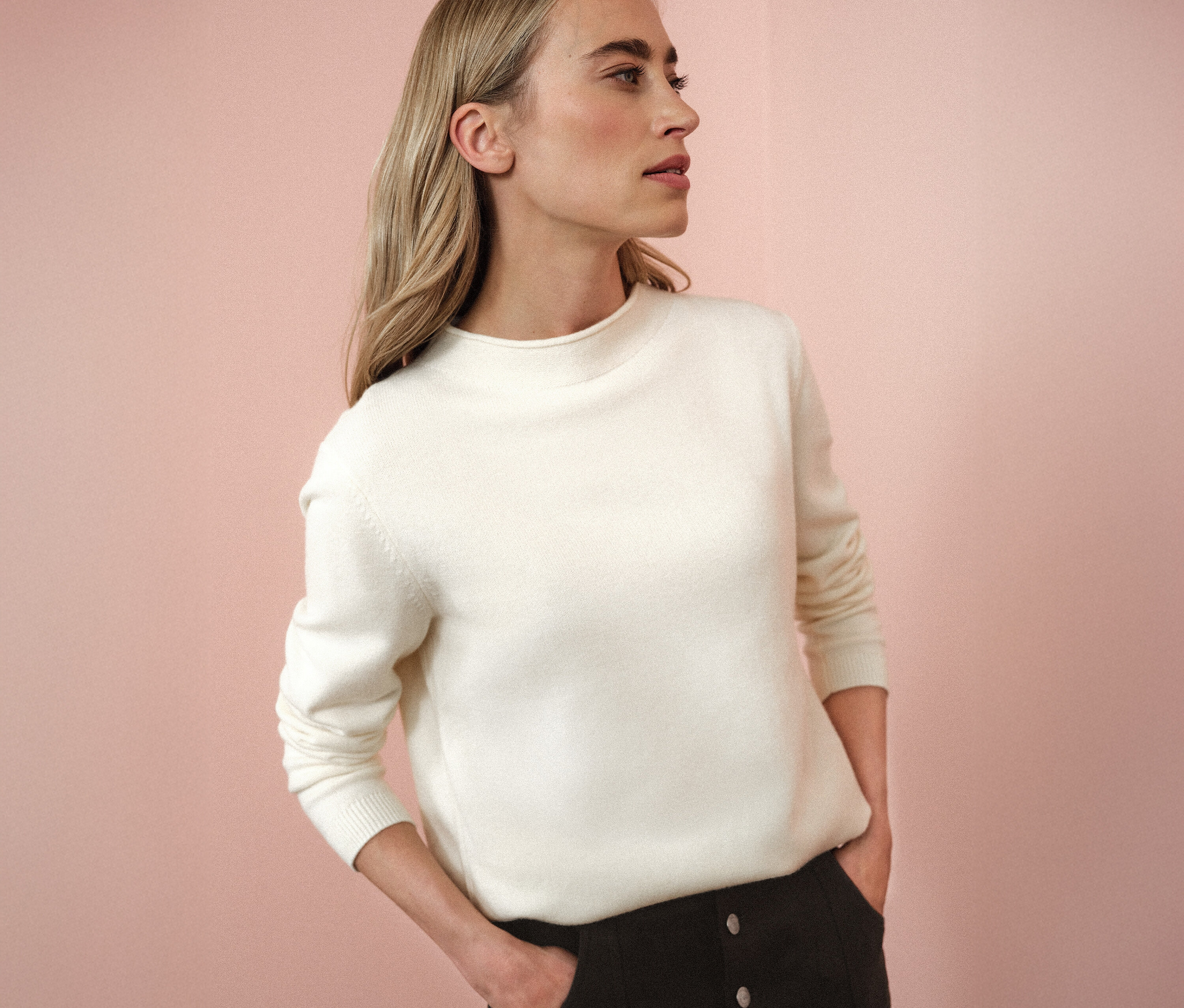 Femme portant un pull en tricot à bord roulé beige.