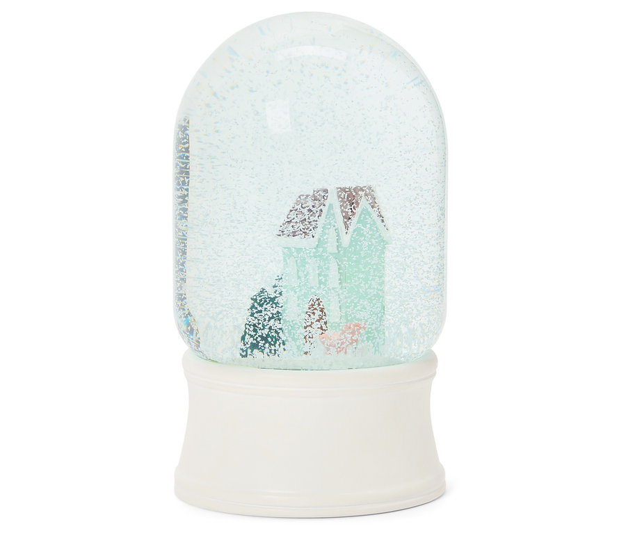 Boule à neige avec une maison à l'intérieur sur un socle blanc.